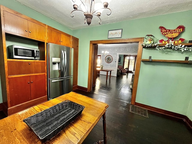 kitchen with visible vents, baseboards, a textured ceiling, a notable chandelier, and stainless steel appliances