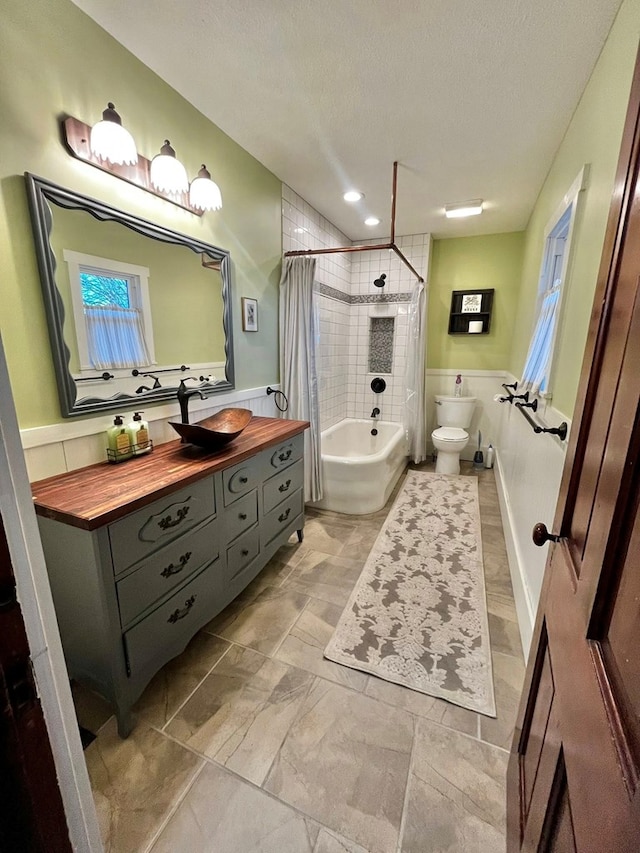 full bath with a textured ceiling, vanity, toilet, shower / tub combo with curtain, and recessed lighting