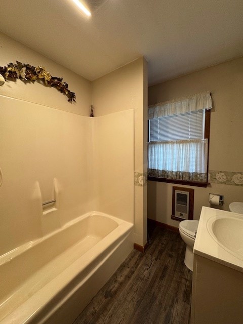 full bathroom featuring hardwood / wood-style floors, vanity, heating unit, bathtub / shower combination, and toilet