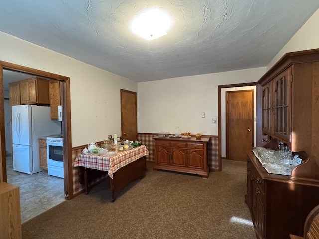 carpeted bedroom featuring white refrigerator and a textured ceiling