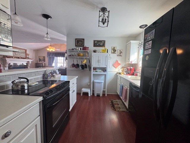 kitchen with white cabinetry, hanging light fixtures, black appliances, dark hardwood / wood-style flooring, and decorative backsplash