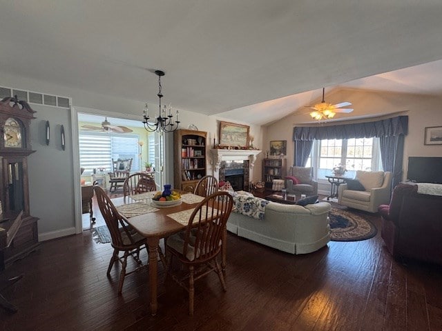 dining area with dark wood-type flooring, lofted ceiling, and ceiling fan with notable chandelier