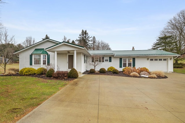 single story home with an attached garage, driveway, metal roof, and a front yard