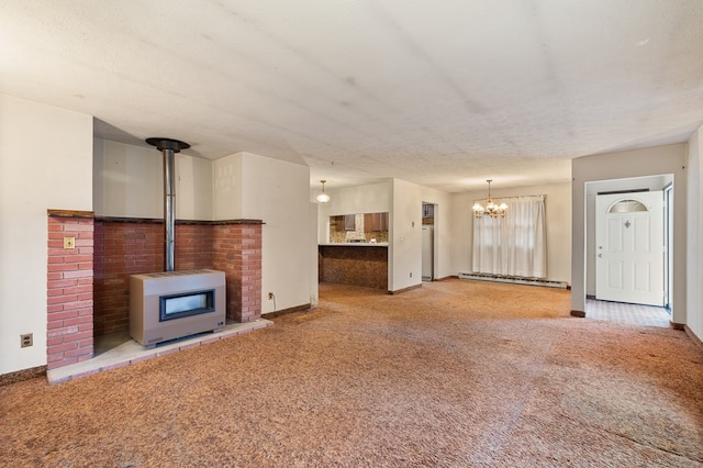 unfurnished living room featuring a wood stove, carpet flooring, a textured ceiling, and baseboard heating