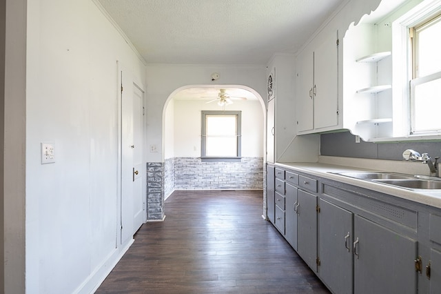 kitchen featuring a textured ceiling, ceiling fan, dark wood-type flooring, sink, and white cabinets