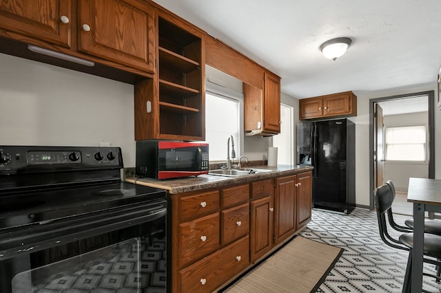 kitchen featuring light floors, open shelves, dark countertops, a sink, and black appliances