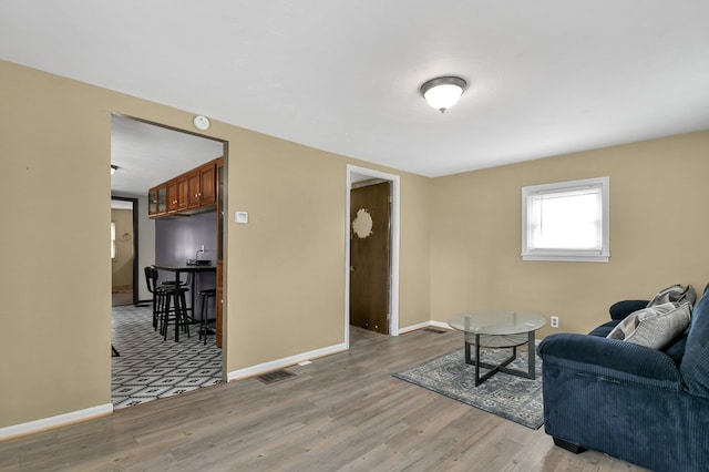 living room featuring light wood-style flooring, visible vents, and baseboards