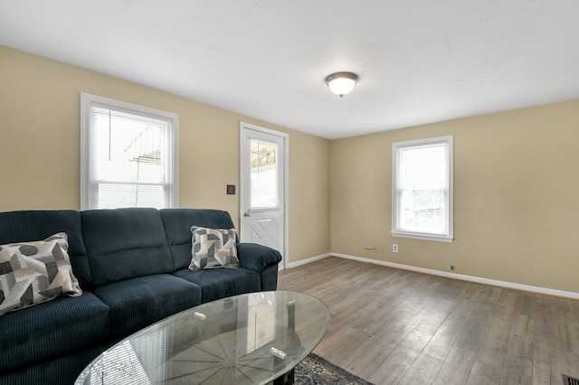 living area with plenty of natural light, baseboards, and wood finished floors