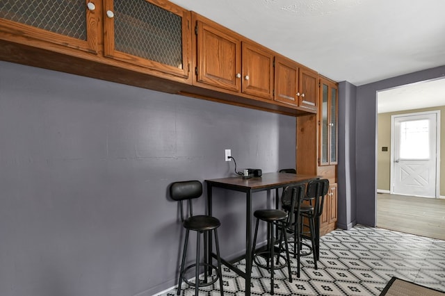 interior space featuring light floors, bar, and baseboards