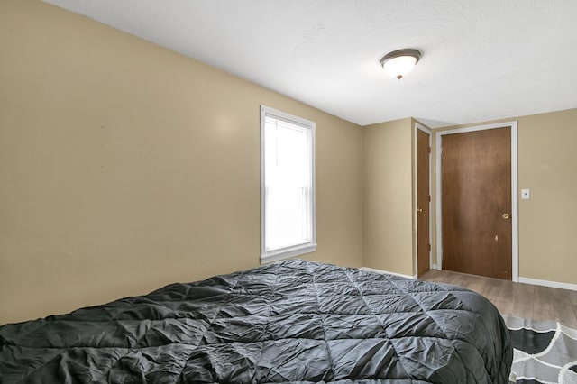 bedroom with a textured ceiling, baseboards, and wood finished floors