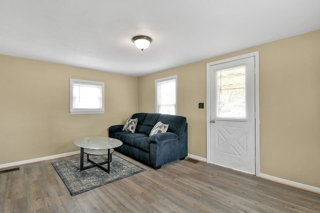 living area featuring baseboards, visible vents, and wood finished floors