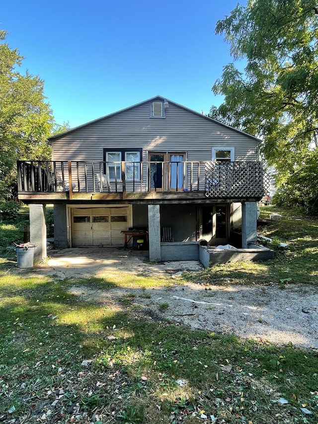 rear view of property with a wooden deck, a yard, and a garage