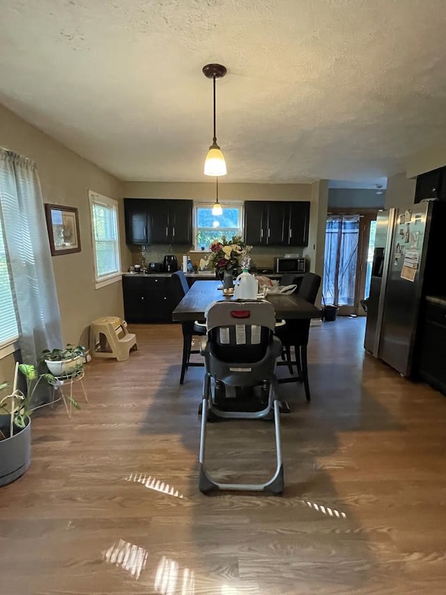 dining space with a textured ceiling, dark wood-type flooring, and a wealth of natural light