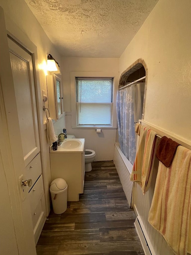 full bathroom with a textured ceiling, toilet, shower / bath combo with shower curtain, vanity, and hardwood / wood-style flooring