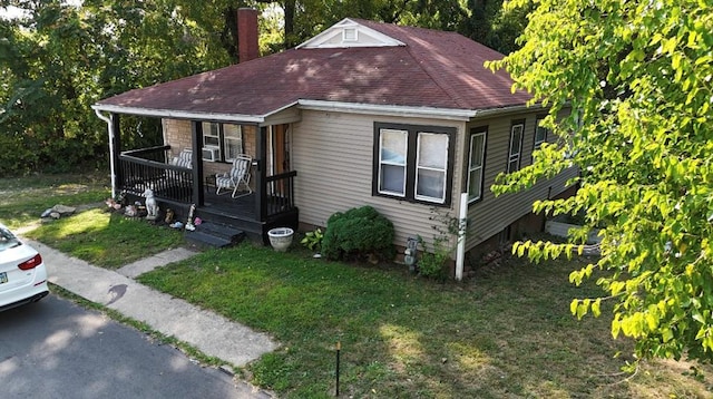 bungalow-style home featuring covered porch and a front lawn