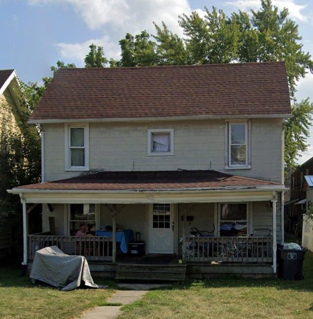 view of front of house featuring covered porch, roof with shingles, and a front yard