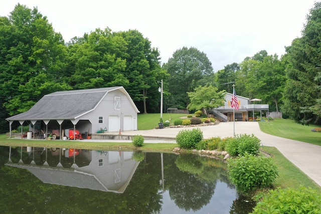 view of community with an outdoor structure, a lawn, a water view, and a carport