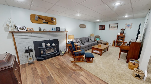 living room with hardwood / wood-style flooring, a wood stove, and a paneled ceiling