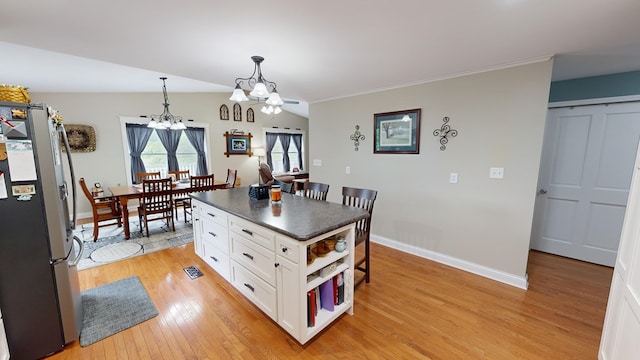 dining area with a notable chandelier, vaulted ceiling, crown molding, and light hardwood / wood-style floors