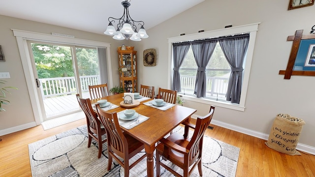 dining area featuring light hardwood / wood-style floors, lofted ceiling, and a notable chandelier