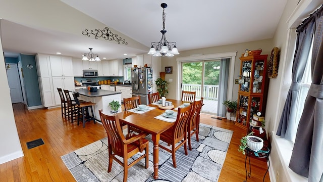 dining space featuring light wood-type flooring, vaulted ceiling, an inviting chandelier, and sink