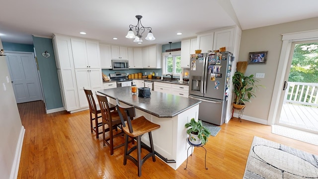 kitchen featuring sink, stainless steel appliances, white cabinetry, and pendant lighting