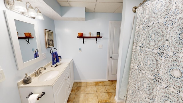 bathroom with a shower with curtain, a drop ceiling, tile patterned flooring, and vanity