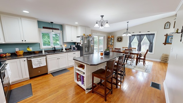 kitchen with sink, stainless steel appliances, vaulted ceiling, and pendant lighting