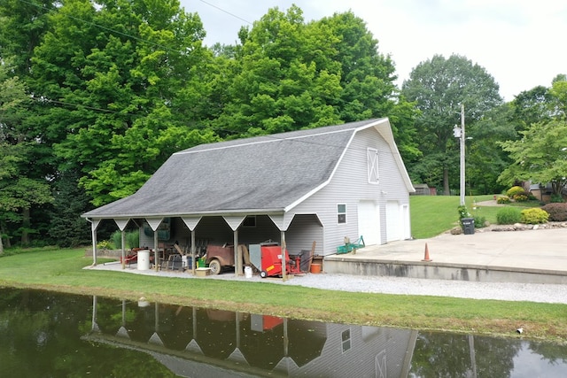 back of property with a water view, a lawn, and a garage