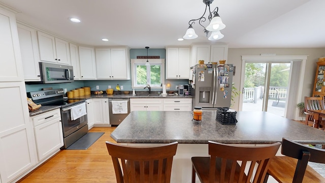 kitchen with stainless steel appliances, white cabinetry, and decorative light fixtures