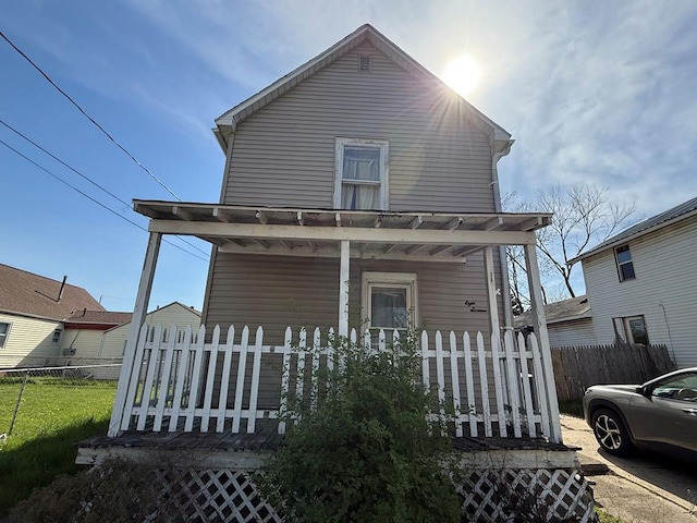 back of property featuring a porch and fence