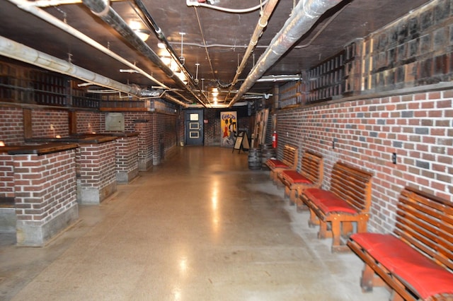 basement featuring brick wall and bar area