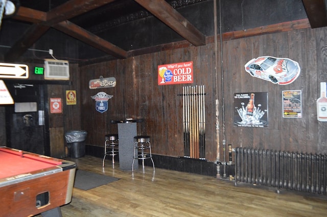 rec room with wooden walls, radiator heating unit, and wood-type flooring