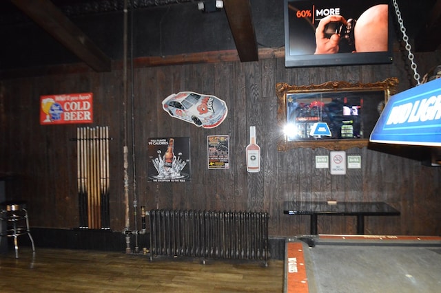 interior space featuring hardwood / wood-style floors, radiator heating unit, beam ceiling, and wood walls