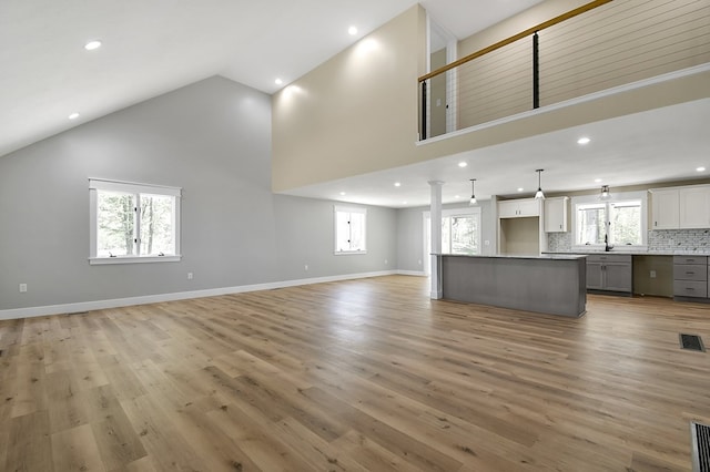 5616 Windfall Rd, Galion, OH 44833 - unfurnished living room featuring recessed lighting, high vaulted ceiling, light wood finished floors, baseboards, and a sink