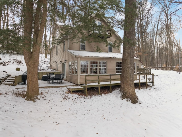 snow covered back of property featuring a deck