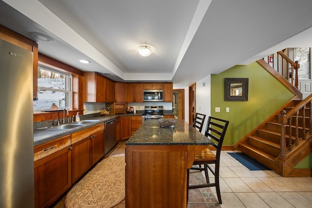 kitchen featuring a center island, a kitchen bar, sink, stainless steel appliances, and a tray ceiling