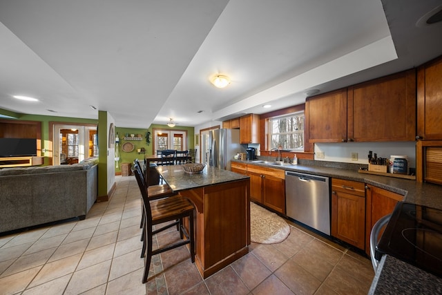 kitchen with a wealth of natural light, appliances with stainless steel finishes, a center island, sink, and a breakfast bar area