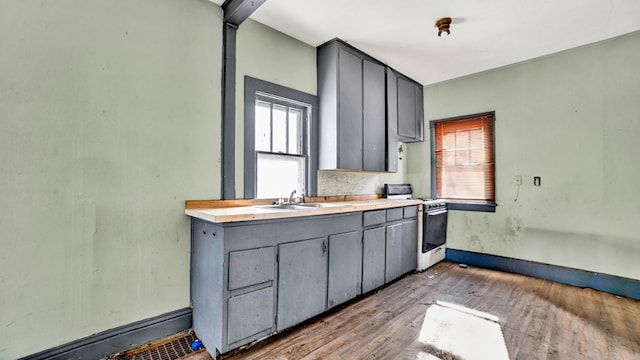 kitchen featuring light hardwood / wood-style flooring, white gas range, gray cabinets, and sink