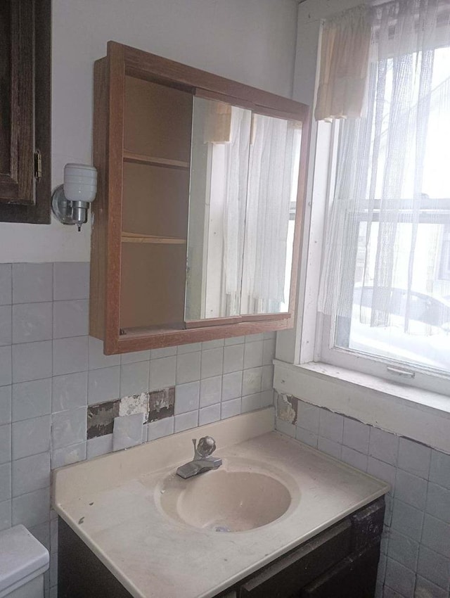 bathroom featuring vanity, toilet, and backsplash