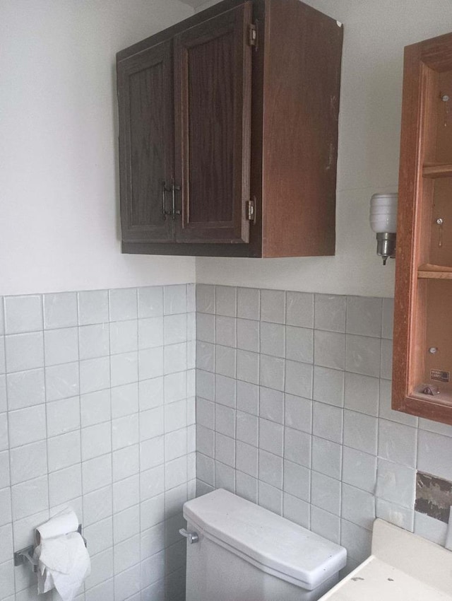 bathroom featuring toilet and tile walls