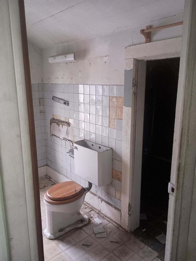 bathroom with toilet and tile walls