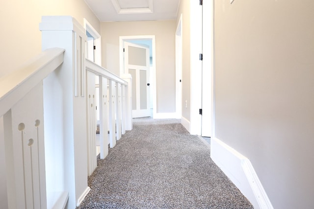 hall featuring baseboards and carpet flooring
