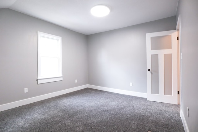 carpeted empty room featuring baseboards and lofted ceiling