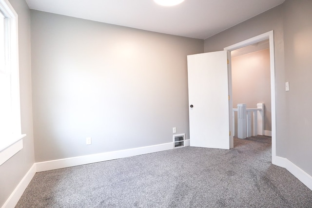 carpeted empty room featuring baseboards and visible vents