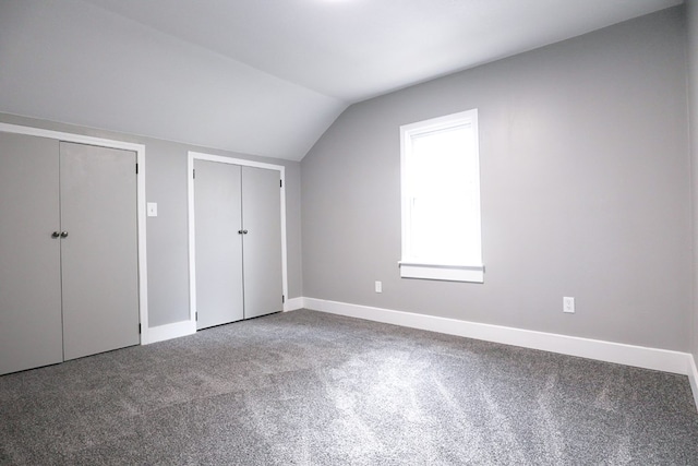 interior space featuring baseboards, lofted ceiling, carpet flooring, and two closets