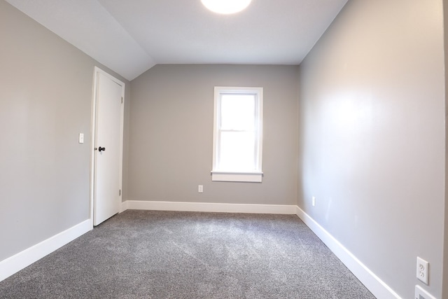 unfurnished room featuring baseboards, vaulted ceiling, and dark colored carpet