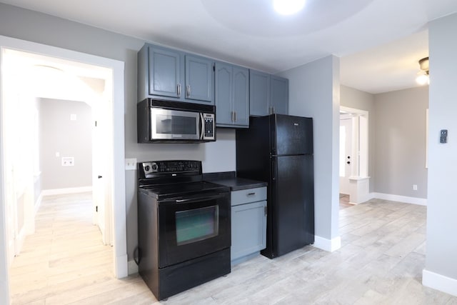 kitchen featuring light wood finished floors, baseboards, dark countertops, and black appliances