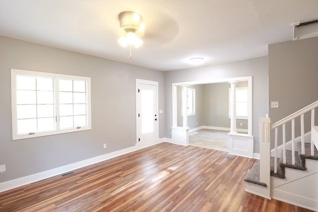 interior space featuring stairway, ornate columns, baseboards, ceiling fan, and wood finished floors