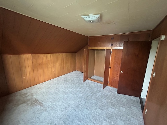 additional living space with carpet floors, wooden walls, and vaulted ceiling